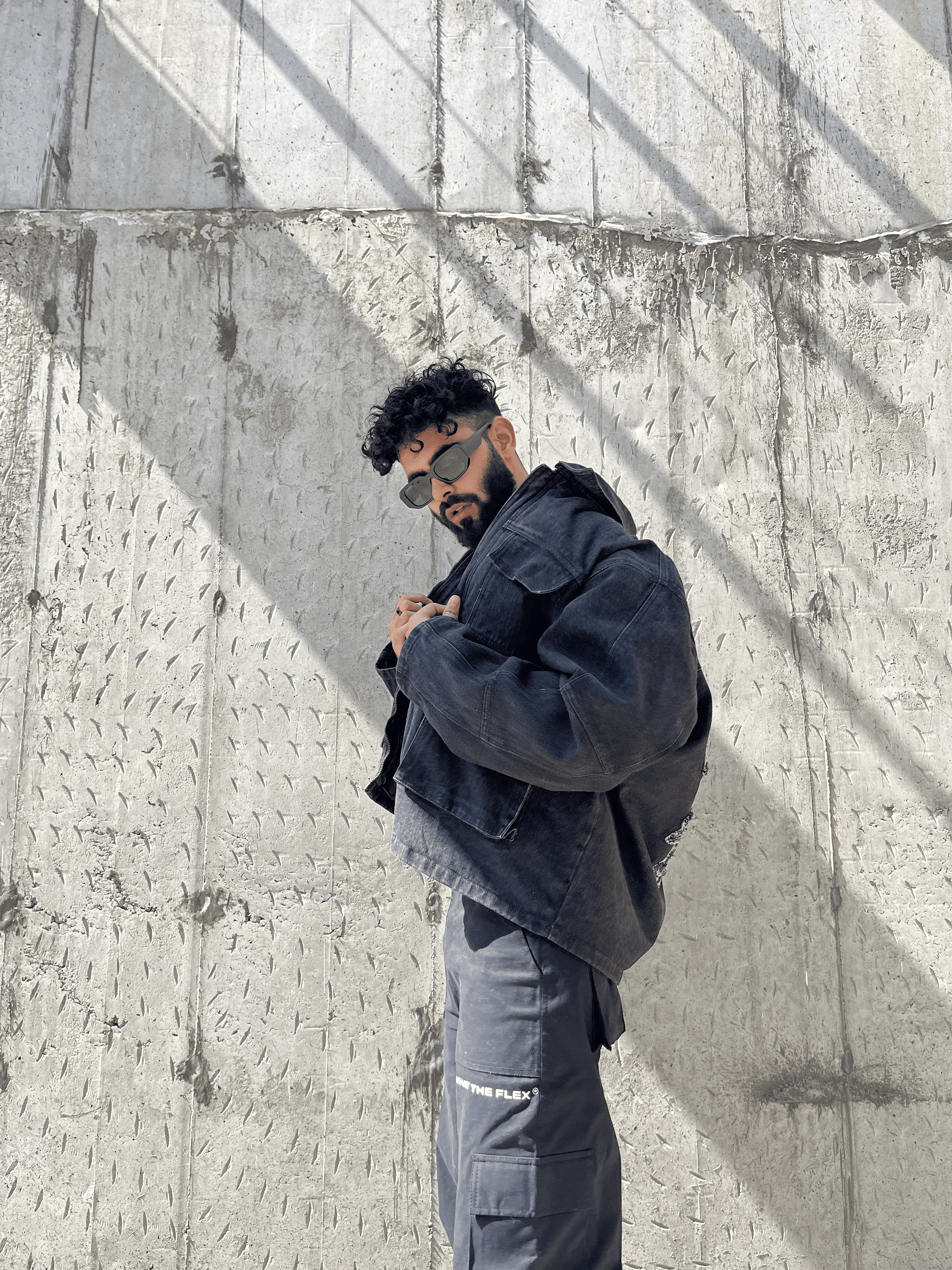 grey streetwear denim jacket and black cargo pants work by a guy